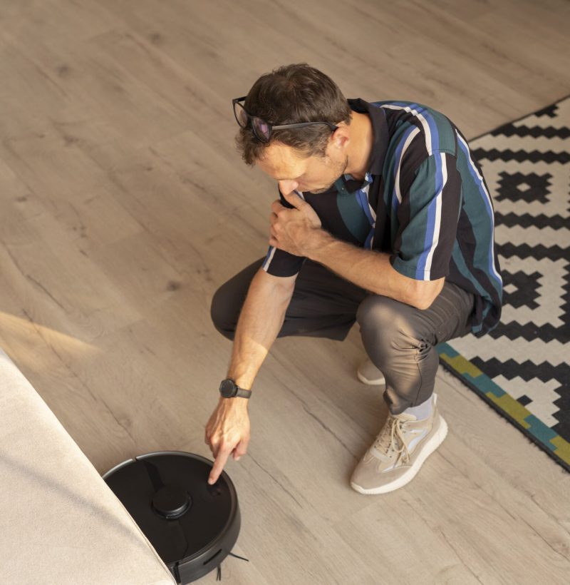 man-using-robot-vacuum-living-room